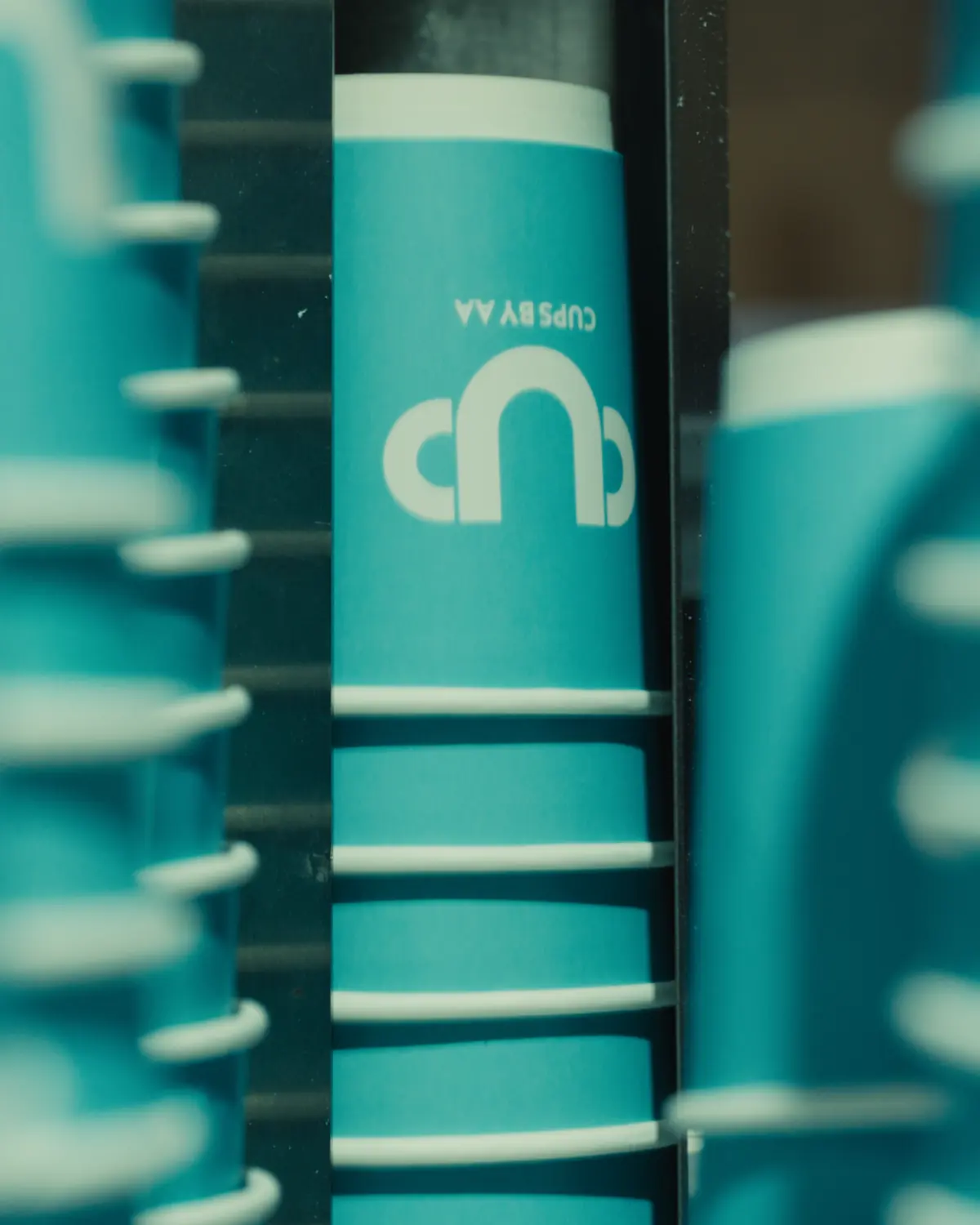 Teal printed cups stacking as they come off the forming machine